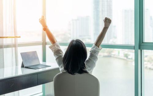 Businesswoman raising fists with ambition looking forward to city building urban scene through glass window concept for How to Start an LLC in Illinois.