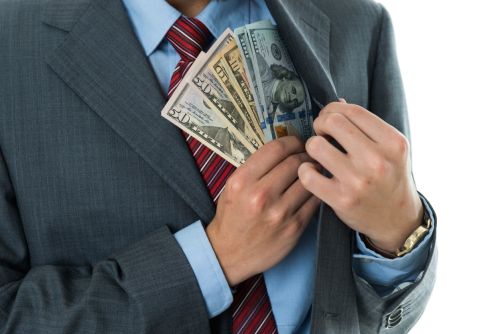 Closeup of businessman putting money in pocket against white background. Visual concept for legal blog titled: What is Self-Dealing in Business?