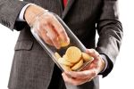 A businessman's hand fishes cookies out of a glass jar. Sweet tooth or metaphor for embezzlement in business.